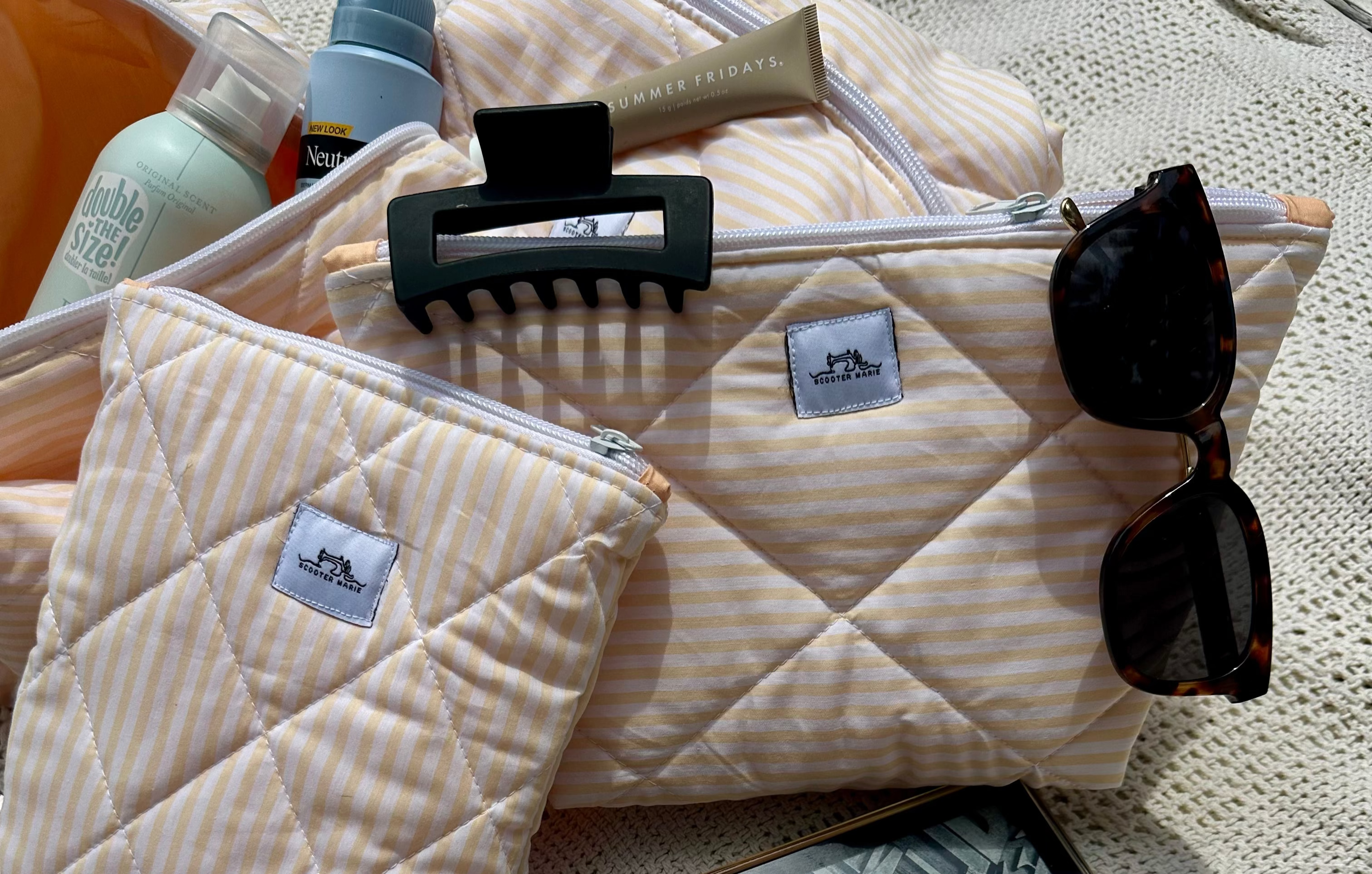 Quilted pouches with a comb, sunglasses, and a tablet on a textured surface